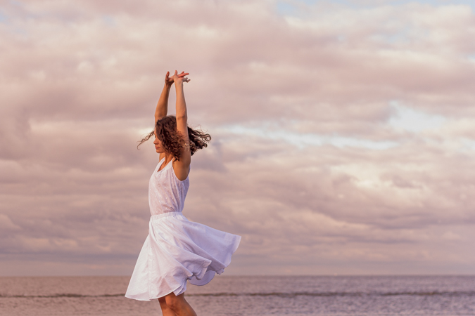 modelo bailando sobre el mar con vestido blanco